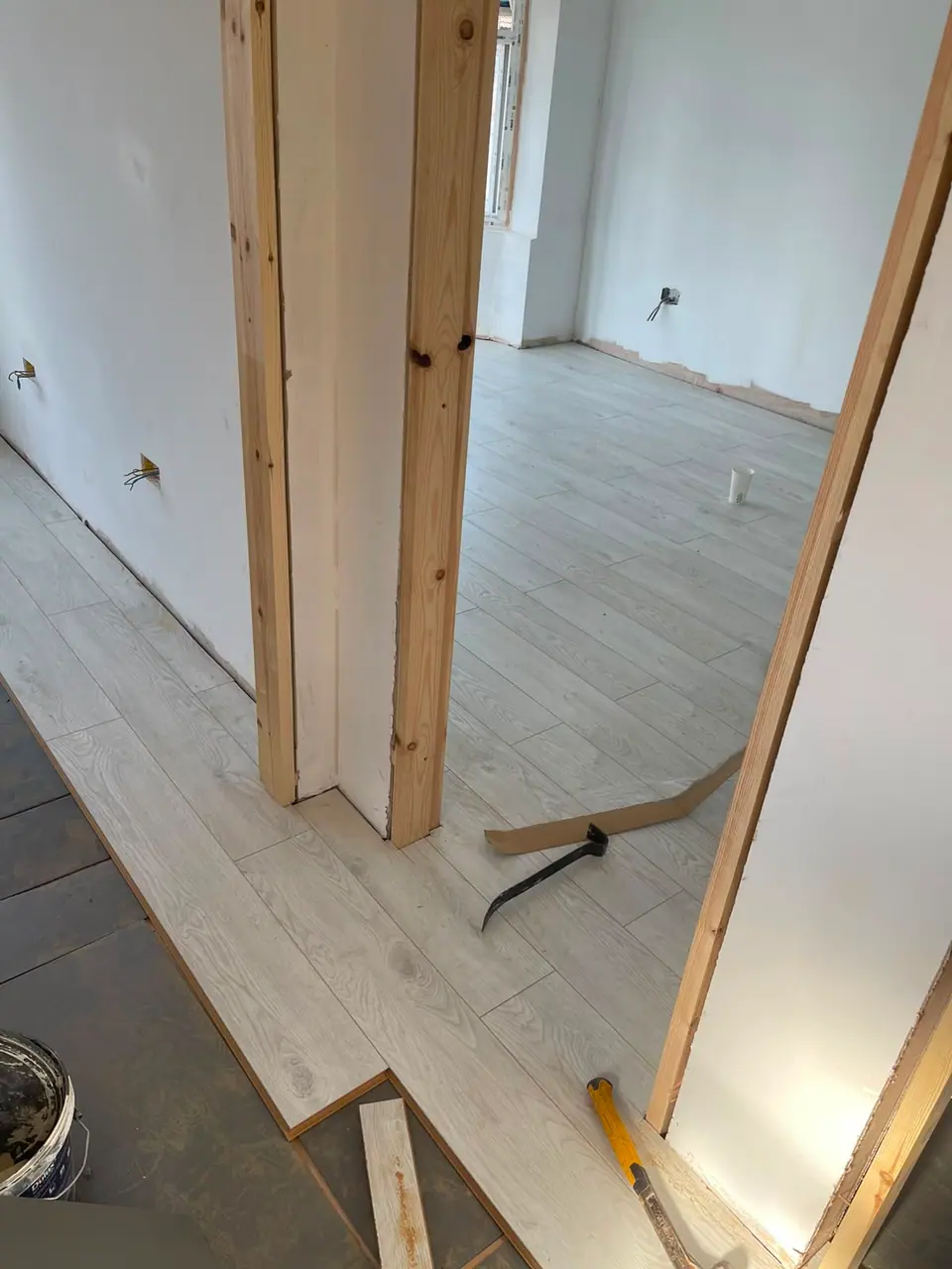 Laminate flooring being laid through timber door linings in a room under refurbishment